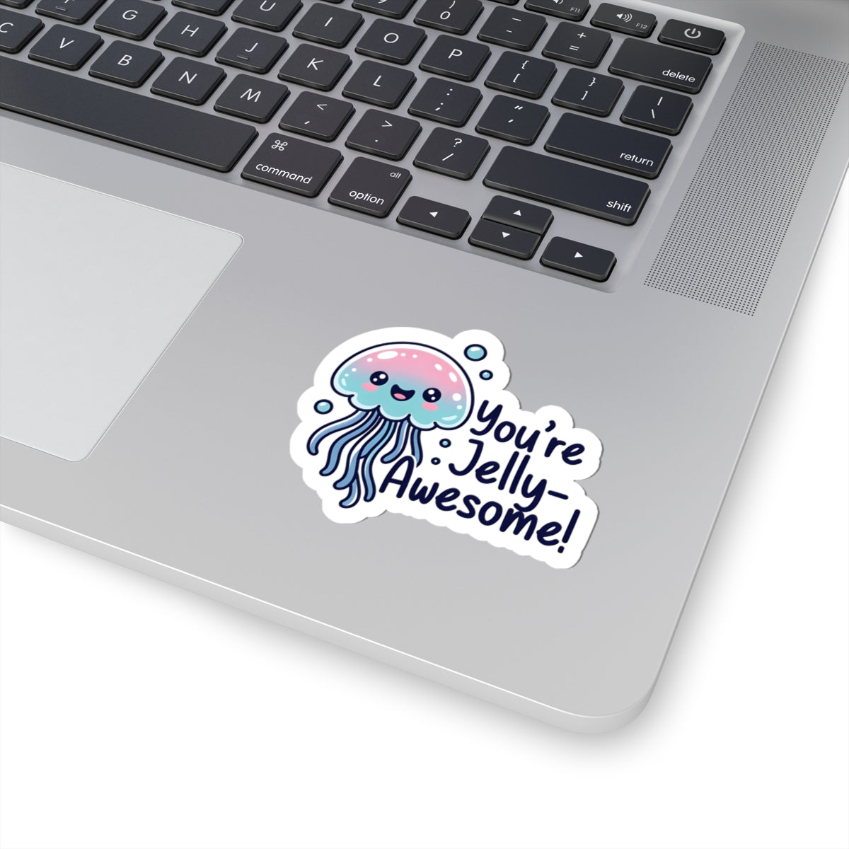 Laptop with a sticker of a jellyfish and text 'You're Jelly Awesome!' on a white surface.