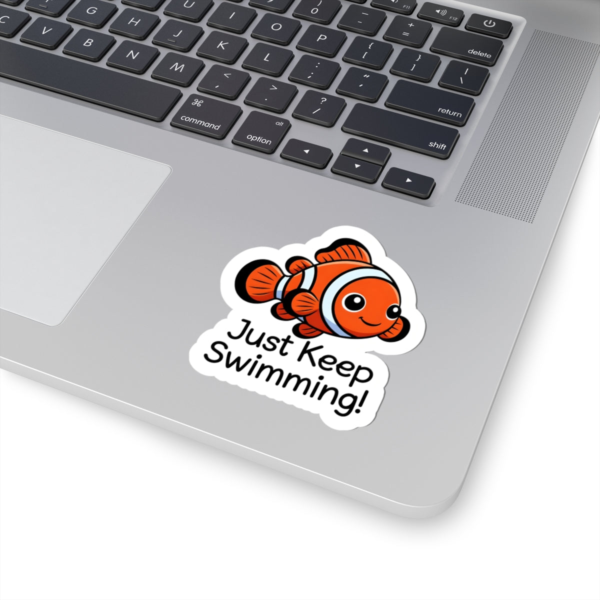 Laptop with a sticker of a clownfish and 'Just Keep Swimming!' text on a white background